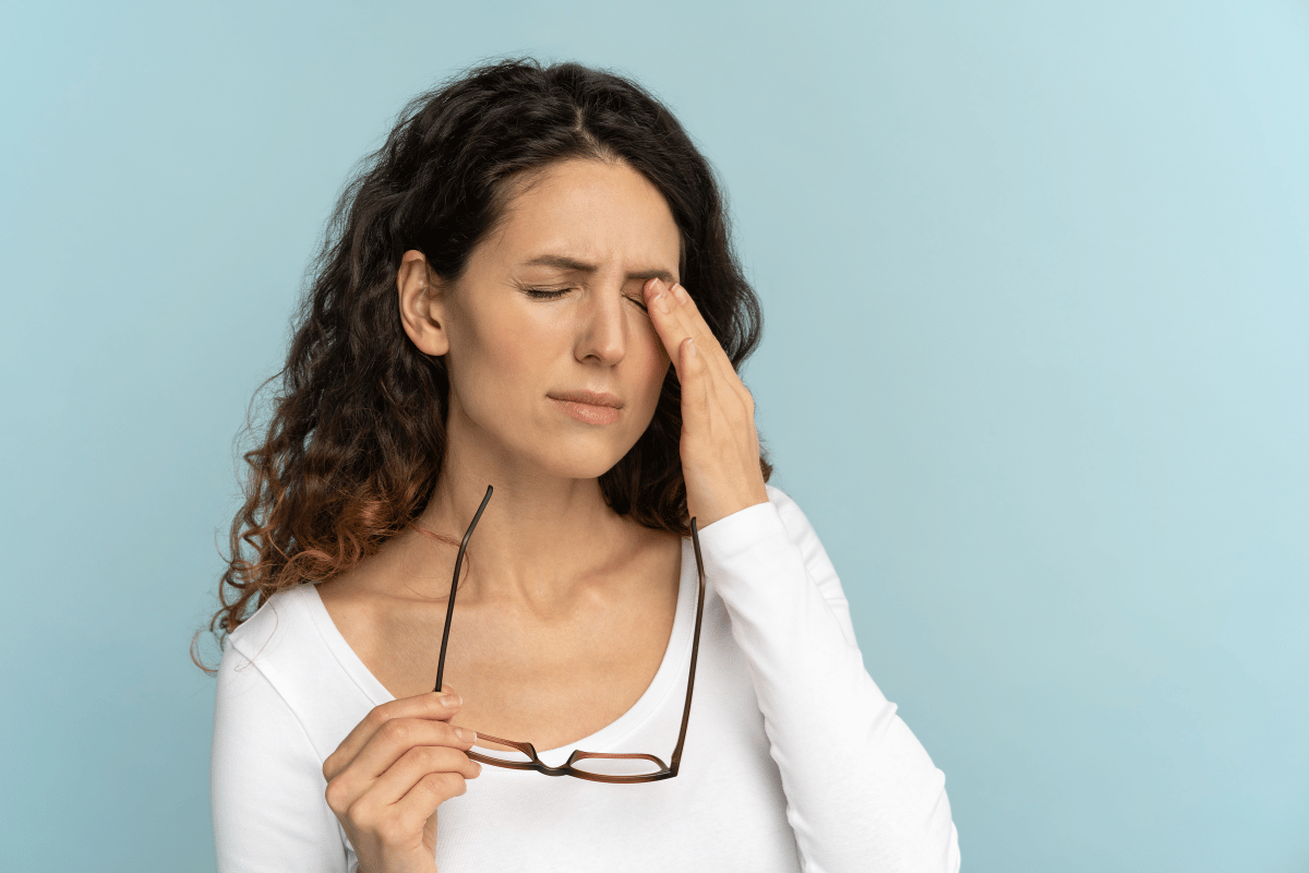 a woman holding a hand to her eye in discomfort