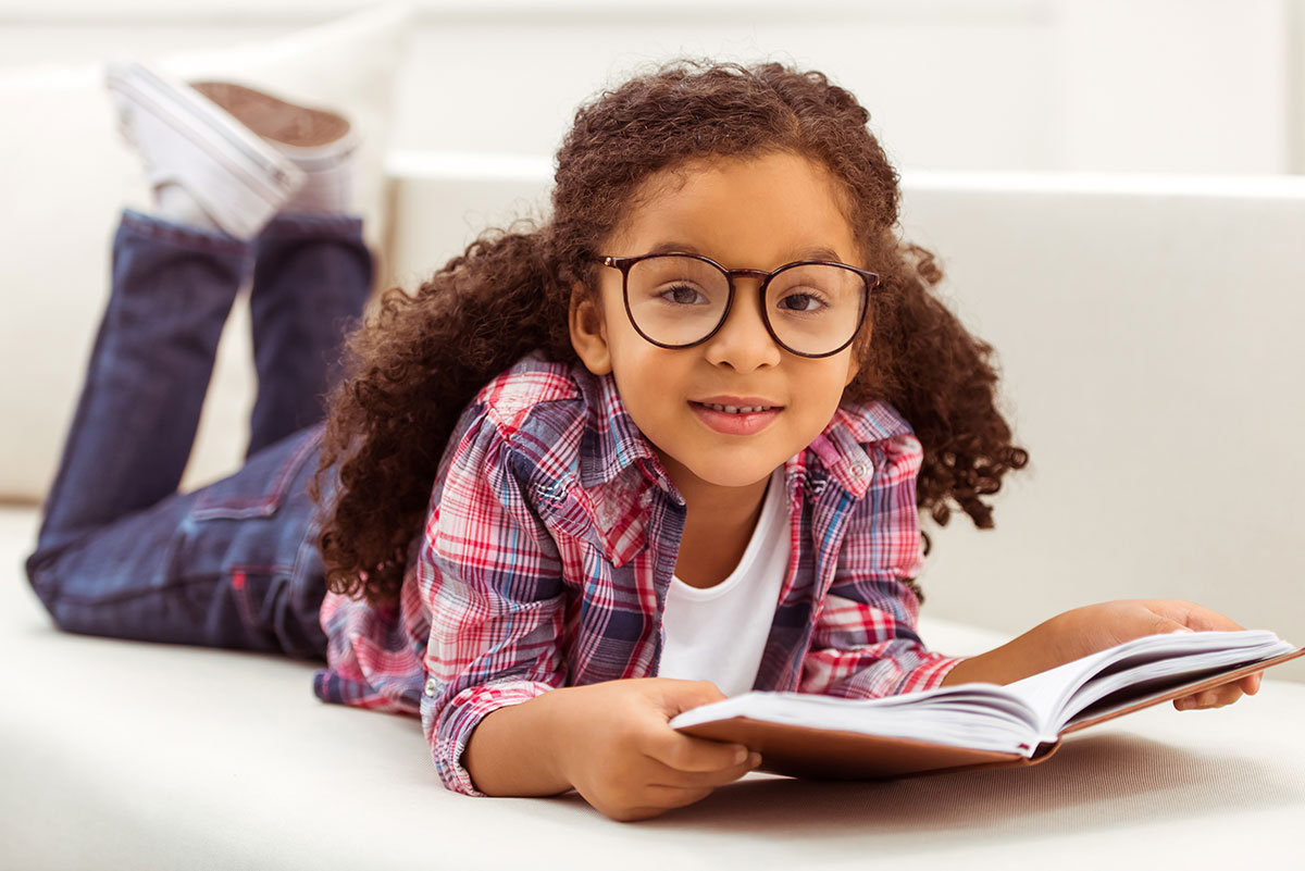 Young girl reading a book in glasses and myopia management treatment