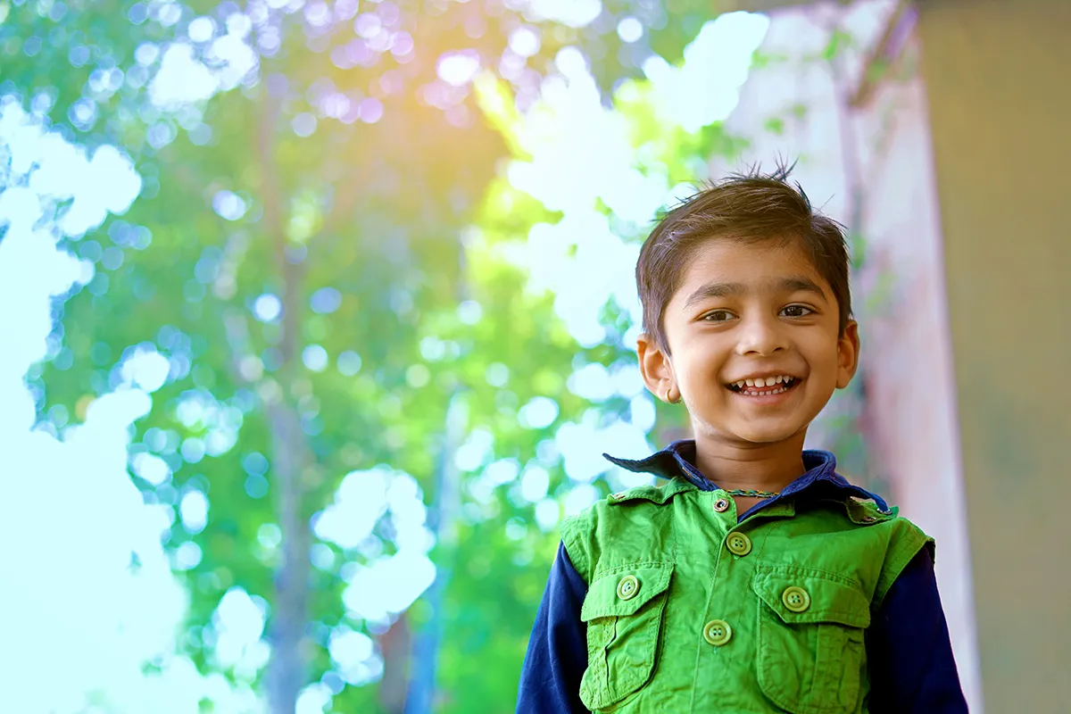 a little boy smiling in front of a window