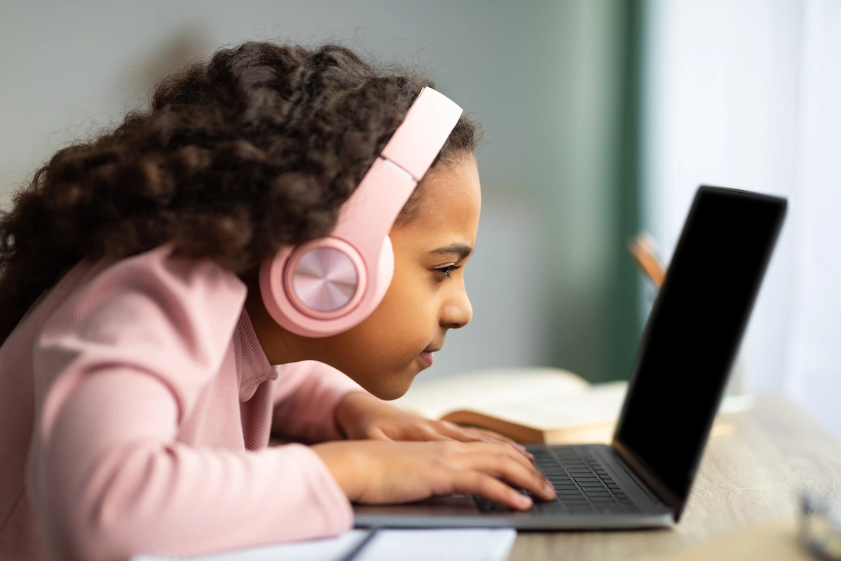Child using laptop, leaning forward and squinting