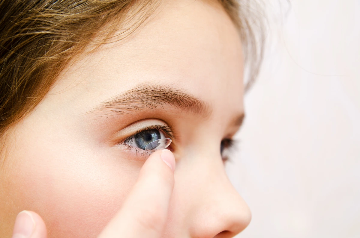 child placing contact lens on eye